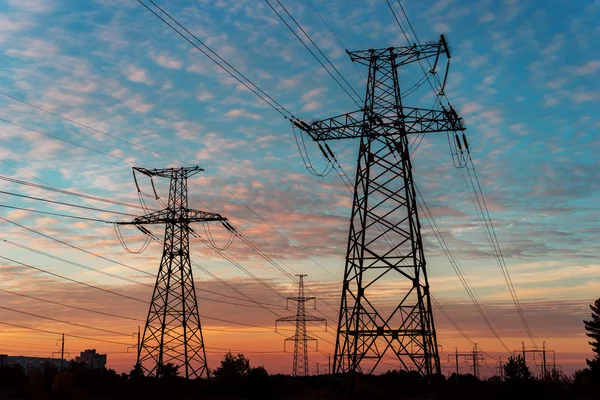 Piloni e linee elettriche al tramonto al tramonto . — Foto Stock