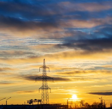 Elektrik direkleri ve gün batımında alacakaranlıkta çizgiler.