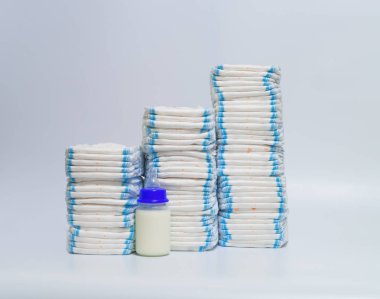 Çocuk bezi ve bebek şişeleri beyaz zemin üzerine yığını.