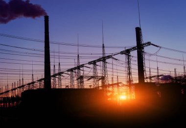 Elektrik hatları ve trafolar olan elektrik santralini gün batımında dağıtın..