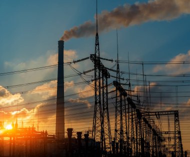 Elektrik hatları ve trafolar olan elektrik santralini gün batımında dağıtın..