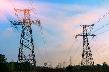Elektrik iletim pilonu alacakaranlıkta mavi gökyüzüne karşı siluetlendi.