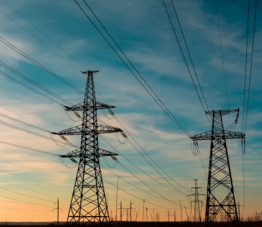 Mavi gökyüzü arka planında elektrik direği silueti var. Yüksek voltaj kulesi.