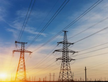 Yüksek gerilim elektrik direği silüeti. Günbatımı gökyüzü arka plan.