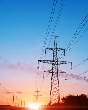 Enerji dağıtım ağı - elektrik direkleri turuncu ve sarı renkli günbatımı karşı.
