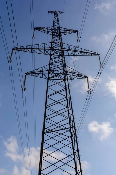 Elettricità pilone sagomato sullo sfondo cielo blu. Torre ad alta tensione — Foto Stock
