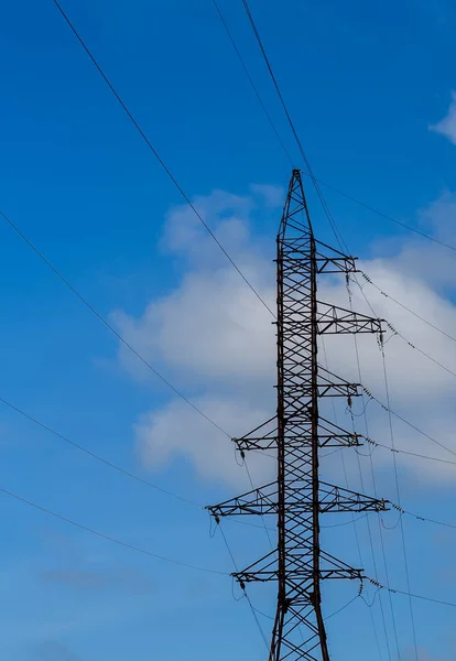 Elettricità pilone sagomato sullo sfondo cielo blu. Torre ad alta tensione — Foto Stock