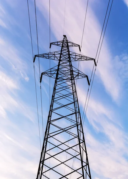 Elettricità pilone sagomato sullo sfondo cielo blu. Torre ad alta tensione — Foto Stock