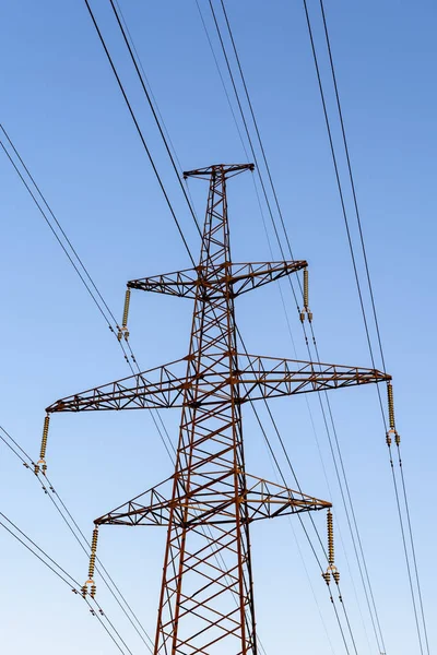 Elettricità pilone sagomato sullo sfondo cielo blu sole. Torre ad alta tensione . — Foto Stock
