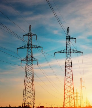 Mavi gökyüzü arka planında elektrik direği silueti var. Yüksek voltaj kulesi.