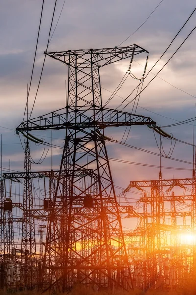 distribution electric substation with power lines and transformers, at sunset.