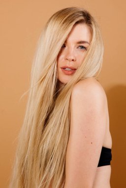 Stüdyoda çıplak arka planda poz veren güzel sarışın kadın portresi.