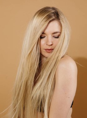 Stüdyoda çıplak arka planda poz veren güzel sarışın kadın portresi.