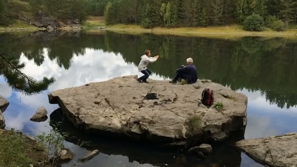Mulher fotografa o homem Smartphone no belo lago movimento lento — Vídeo de Stock
