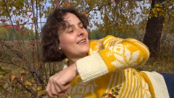 Mooi meisje gooit gele bladeren van een boom. Motion.outdoors herfst zonlicht langzaam — Stockvideo