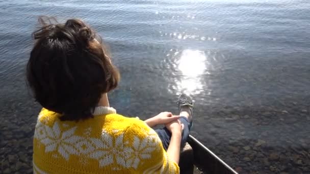 Joven morena chica está sentado en barco en el lago. Antecedentes Sol resplandor en el agua. Cámaras de tráfico — Vídeos de Stock