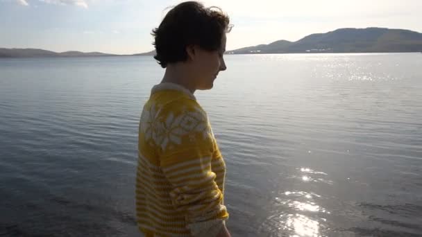 Mooi jong meisje wandelingen langs de oever van het meer in de schittering van de zon. Slow Motion — Stockvideo