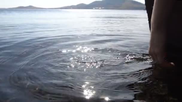 Hand Mädchen im klaren Wasser des Sees. Spiel der Sonnenblendung. Zeitlupe — Stockvideo