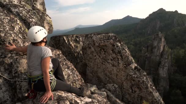 Mujer escaladora admirando el paisaje rocoso en la parte superior. Día soleado frente al atardecer — Vídeos de Stock