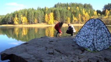 Kız ve erkek köpek turistler ile oynuyor. Sonbahar çadır