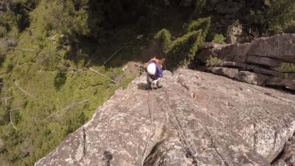 Femme grimpeuse escalade une falaise avec une corde. L'été. Journée ensoleillée — Video