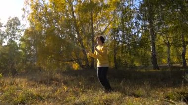 Ağır çekim akrobasi genç kız güneşli sonbahar ormandaki bir ip ile.