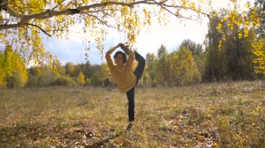 Ağır çekim kız akrobasi arka plan Leaf Fall. Güneşli gün.