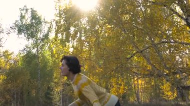 Ağır çekim kız akrobasi arka plan Leaf Fall. Güneşli gün.
