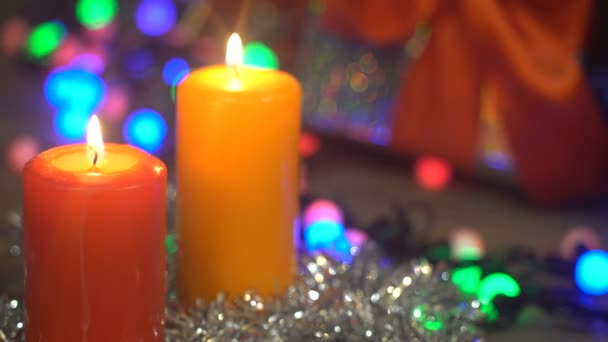Dos velas de Navidad se queman en un regalo de fondo borroso — Vídeos de Stock
