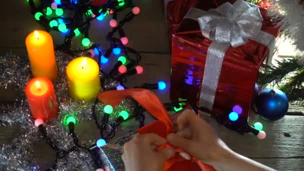 キャップ サンタで女性がクリスマス ツリーの下にクリスマス プレゼントをラップします。 — ストック動画