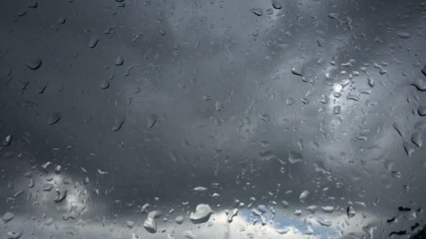 Dešťové kapky běží dolů na skle na pozadí zamračená obloha — Stock video