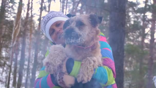 Mujer con un perro en un picnic junto al fuego. Día de invierno — Vídeos de Stock