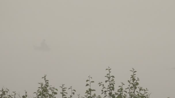 Barco con un pescador en una niebla brumosa en la mañana — Vídeos de Stock