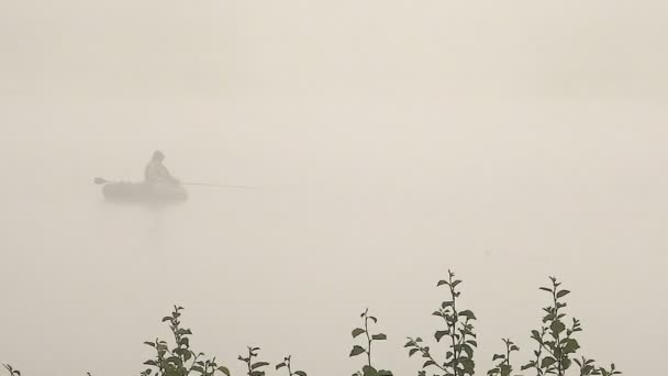 Barco con un pescador en una niebla brumosa en la mañana — Vídeos de Stock