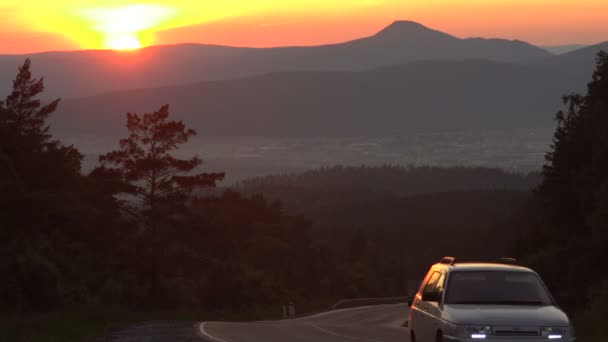 Bilens tid varv på natten på motorvägen i bergen mot solnedgången — Stockvideo