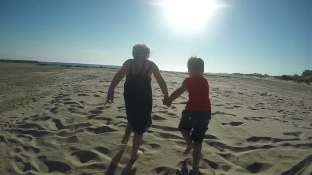 Meisje en jongen loopt over het zand — Stockvideo