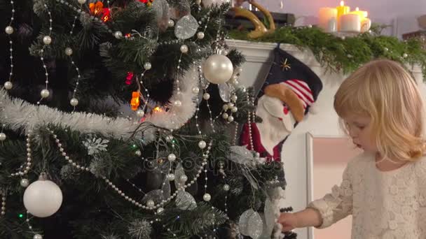 Pequena menina bonita decora uma árvore de Natal — Vídeo de Stock