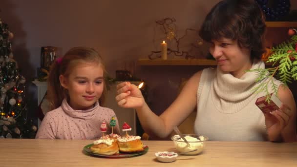 母と娘は、クリスマスのキャンドルを点灯してください。 — ストック動画
