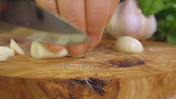 Snijden knoflook op een houten snijplank — Stockvideo