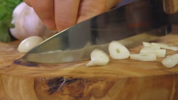 Snijden knoflook op een houten snijplank — Stockvideo