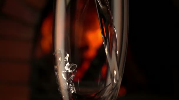 Champagne wordt gegoten in een glas op een achtergrond van brand — Stockvideo