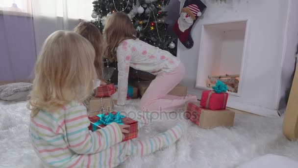 Niña elige un regalo cerca del árbol de Navidad — Vídeo de stock