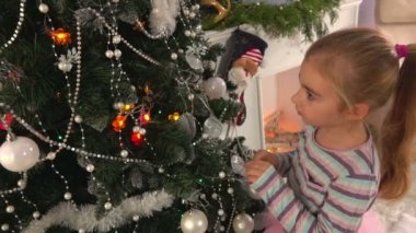 küçük kız bir Noel ağacı süsle