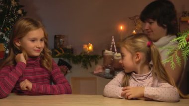 Anne masaya bardak sıcak çikolata ile bir tepsi koyar.