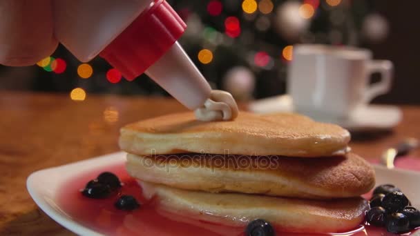 Confectionery syringe puts cream in stack of pancakes