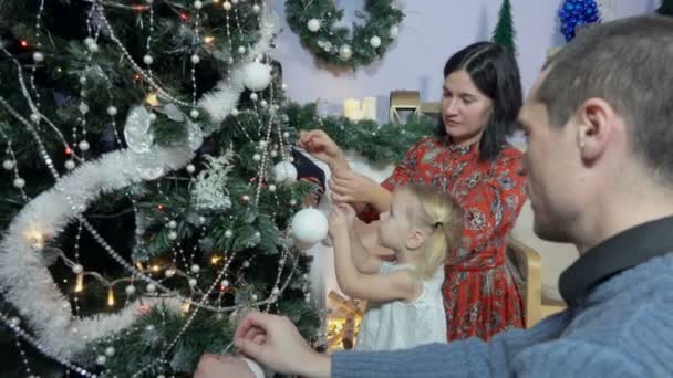Klein meisje siert een kerstboom — Stockvideo