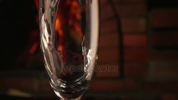 El champán se vierte en una copa sobre un fondo de fuego — Vídeos de Stock