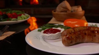 Akşam yemeği ızgara sosis ile bir tabak koyun elleri