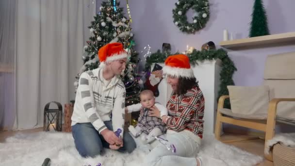 Familia con el bebé en los sombreros de Santas explota una galleta — Vídeo de stock