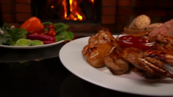 Hand op tafel gelegd op een plaat van gebakken kippenvleugels — Stockvideo